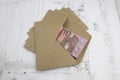 A bundle of 10 euro banknotes lies in a brown envelope on a pile of envelopes.