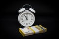 Bundle of 200-euro banknotes is lying in front of a white alarm clock with its hands set to 5 minutes to 12 Royalty Free Stock Photo