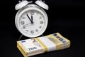 Bundle of 200-euro banknotes is lying in front of a white alarm clock with its hands set to 5 minutes to 12 Royalty Free Stock Photo