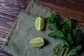 Bundle of fresh mint and lime slice on a napkin on an old woode