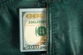 A bundle of hundred-dollar bills sticks out of the pocket of a leather jacket of green color. Shooting close-up