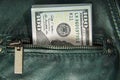 A bundle of hundred-dollar bills sticks out of the pocket of a leather jacket of green color. Shooting close-up