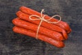 Bundle of long thin smoked sausages on the black surface