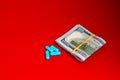 Bundle of money and blue pharmaceutical pills, medicines on a red background. Royalty Free Stock Photo