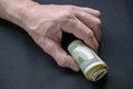 Bundle of rolled up dollar bills clutched in caucasian man`s hand. Male holding cash money currency of United States Royalty Free Stock Photo