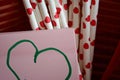 Bundle of straws with printed hearts and a sticky note with a green heart on. Royalty Free Stock Photo