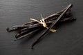 Bundle of tied, dried bourbon vanilla beans or pods on black stone board flat lay top view