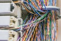 Bundles of multicolored wires intertwined with each other in the rack of the data center server room. The colored wires are