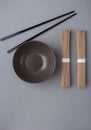 Bundles of Soba Noodles Dark Empty Bowl Black Bamboo Chopsticks on Grey Background. Japanese Chinese Asian Cuisine. Menu Poster Royalty Free Stock Photo