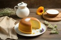 a bundt cake on a plate with a slice cut out of it next to a cup of coffee and a vase with flowers on a wooden table Royalty Free Stock Photo