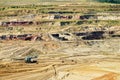 Bunk wall surface mine with exposed colored minerals and brown coal, the pit mining equipment Royalty Free Stock Photo