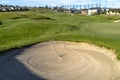 Bunker and fairway of a golf course with homes mountain and sky background