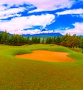 Bunkers Around Golf Putting Green and Colorful Plants with Beautiful Blue Sky and Cloudy Mountain Royalty Free Stock Photo