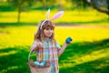 Bunny child with hunting easter eggs. Easter bunny children. Kids boy in bunny ears hunting easter eggs in park outdoor.
