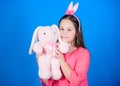 Bunny ears accessory. Lovely playful bunny child hugs soft toy. Bunny girl with cute toy on blue background. Child