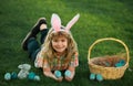 Bunny kids with rabbit bunny ears. Child hunting easter eggs in backyard laying on green grass. Royalty Free Stock Photo