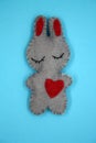 A bunny made of gray felt with a red heart