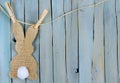 Bunny shape in burlap with a cotton swab tail hanging from twine by clothespins.