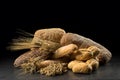 Buns, baguette, ciabatta and bread on dark wooden table. Rye, barley, wheat, oats and many fresh mixed breads on black ba Royalty Free Stock Photo