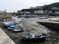 Bunte Fischerboote und Ruderboote liegen bei Ebbe auf dem Sandboden des Hafens von Porthleven