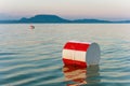 Buoys with red and white stripes on the blue water of Lake Balaton with the Badacsony mountan in the background in Hungary