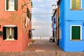 Burano island picturesque street and courtyard with small colorful houses in row against cloudy blue sky and Adriatic Royalty Free Stock Photo