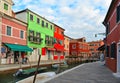 Burano island picturesque street with small colored houses in row, water canal with fishermans boats, cloudy blue sky Royalty Free Stock Photo