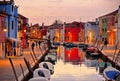 Burano island picturesque street with small colored houses, tourists on street and beautiful water reflections on cana Royalty Free Stock Photo