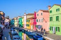 Daylight view to a street with colorful buildings and people wal