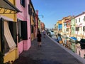 A young female tourist by herself exploring the beautiful view of the famous canals and colourful homes of the town of Burano