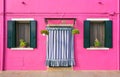 BURANO, ITALY - 2 September, 2016. Pink color of the walls, two windows, flowers on the windowsill. Typical view of Burano islan Royalty Free Stock Photo