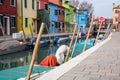 Typical street scene showing brighly painted houses, mooring posts and canal on the island of Burano, Venice.