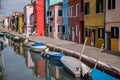 Burano, Italy. Typical street scene showing brightly painted houses reflected in the canal, with boats. Royalty Free Stock Photo