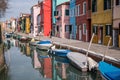 Burano, Italy. Typical street scene showing brightly painted houses reflected in the canal, with boats. Royalty Free Stock Photo