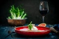 Burata cheese with dried tomatoes, artichokes, arugula and Basil on a red plate. A dish of Italian cuisine Royalty Free Stock Photo