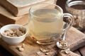 Burdock root tea in a glass cup with dry herb and old apothecary books nearby on wooden rustic background, Royalty Free Stock Photo