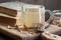 Burdock root tea in a glass cup with dry herb and old apothecary books nearby on wooden rustic background Royalty Free Stock Photo