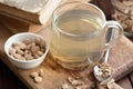 Burdock root tea in a glass cup with dry herb and old apothecary books nearby on wooden rustic background, Royalty Free Stock Photo