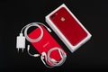 BURGAS, BULGARIA - AUGUST 10, 2018: Apple iPhone 7 Plus Red Special Edition on black background, back side. Charger and earpods. Royalty Free Stock Photo