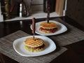 Burger with beef chops, guacamole, cherry sauce, potato bun on the grill. Stabbed with a knife with a wooden handle Royalty Free Stock Photo