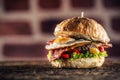 Burger with beef, egg, bacon, salad, peppers in a rustic environment