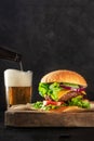 Burger and beer. Cheeseburger with beef, cheese, onion, tomato, and green salad Royalty Free Stock Photo