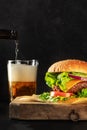 Burger and beer. Hamburger with beef, cheese, onion, tomato, and green salad Royalty Free Stock Photo