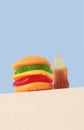 Burger and bottle shape gummy candy on white podium, blue background. Sweet food concept Royalty Free Stock Photo