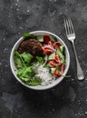 Burger bowl. Beef patty with rice and fresh vegetable salad on a dark background, top view