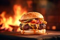 Burger with cheese, lettuce, sauce, cucumber and fries on a wooden board, fire in the background