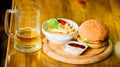 Burger with cheese meat and salad. Pub food and mug of beer. Fast food concept. Burger menu. High calorie snack