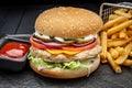 Burger with chicken cutlet and french fries on a dark background Royalty Free Stock Photo