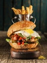 Burger with chopped meat, egg and arugula on a wooden table Royalty Free Stock Photo