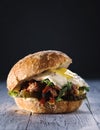 Burger with chopped meat, egg and arugula on a wooden table Royalty Free Stock Photo